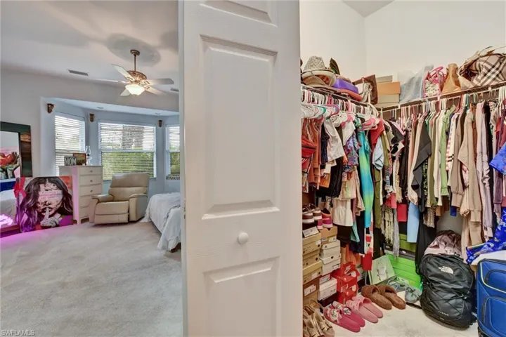 Walk in closet with ceiling fan and carpet flooring