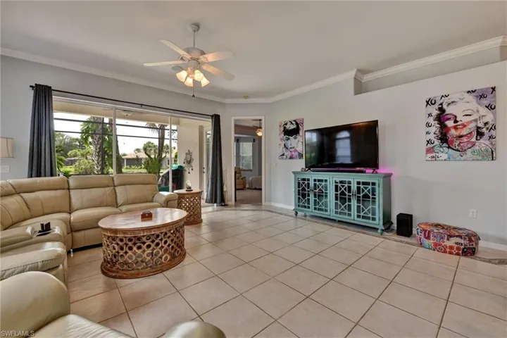 Living room with ceiling fan, crown molding, and light tile floors