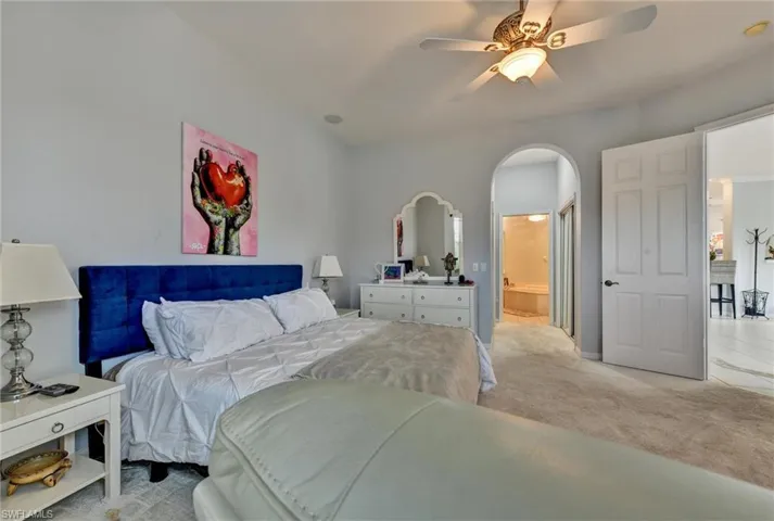 Bedroom with ensuite bathroom, carpet, and ceiling fan