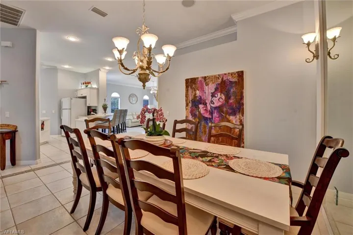 Dining area with a notable chandelier, ornamental molding, and light tile flooring