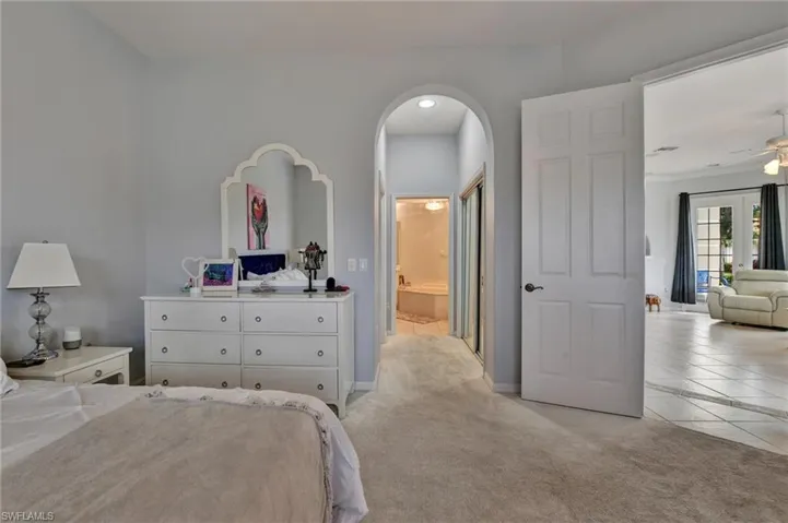 Carpeted bedroom featuring ceiling fan and ensuite bath