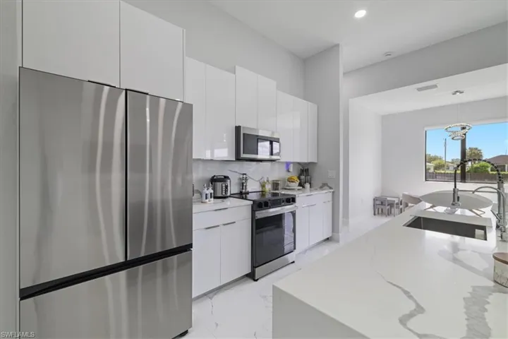 Kitchen with stainless steel appliances, light marble finish flooring, modern cabinets, hanging light fixtures, and recessed lighting