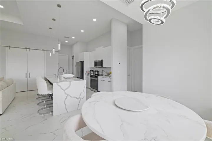 Kitchen with pendant lighting, an island with sink, a breakfast bar, open floor plan, and modern cabinets