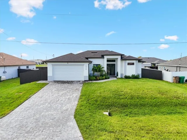 Prairie-style home with stucco siding, decorative driveway, and a garage