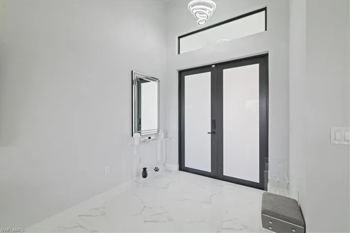 Entrance foyer featuring marble tiled flooring, french doors, and a towering ceiling