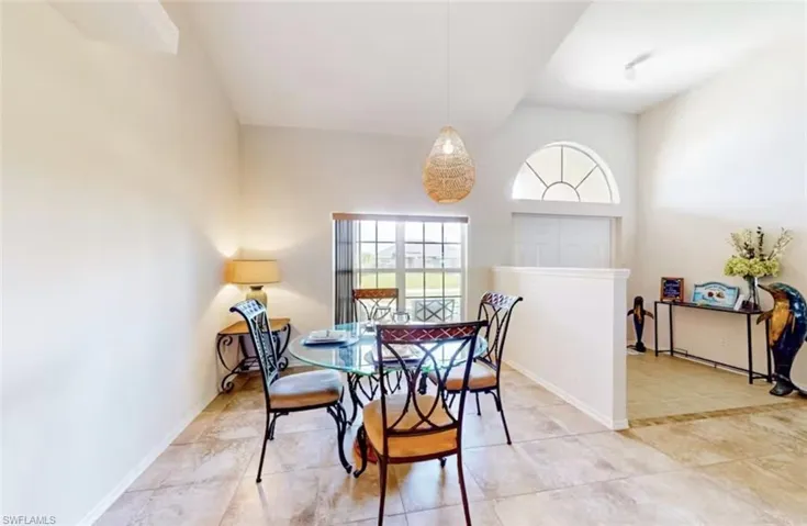 Dining area featuring vaulted ceilings and neutral-toned tile flooring