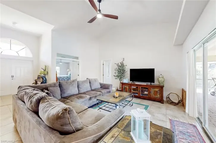 Living area featuring vaulted ceilings, ceiling fan, and tile flooring