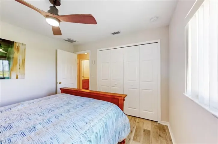 Interior room featuring wood-finish flooring, a ceiling fan with integrated lighting, and a window with vertical blinds