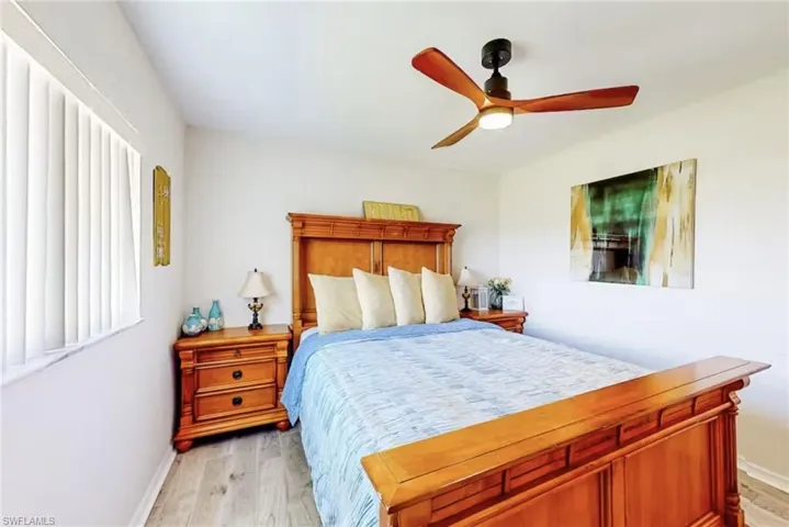 Bedroom featuring light wood-finish flooring, white walls, and a modern ceiling fan with wooden blades