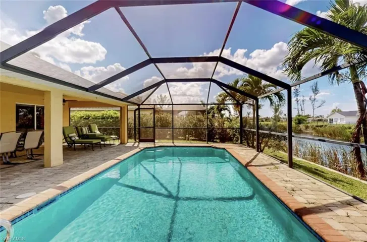 Screened-in pool area featuring a rectangular pool, paver deck, and covered patio space