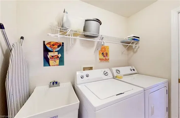 Dedicated laundry space featuring a utility sink with faucet, side-by-side appliance hookups, and integrated wire shelving for storage
