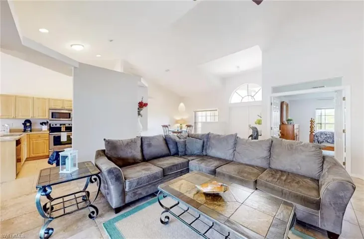 Spacious living area featuring vaulted ceilings, tile flooring, and an arched window