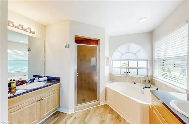 Corner soaking tub with a tiled surround and an arched window