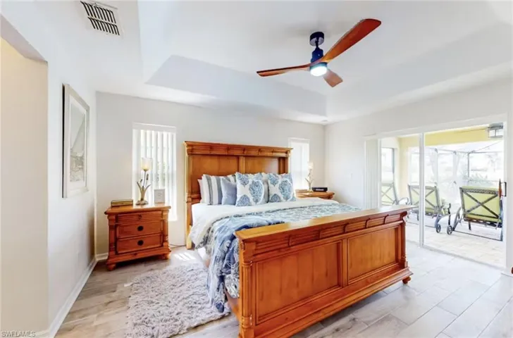 Tray ceiling with a built-in ceiling fan, wood-finish flooring, and vertical window blinds