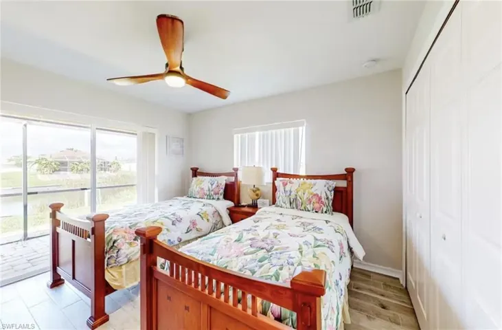 Sliding glass doors opening to a screened patio, wood-finish flooring, a ceiling fan with integrated lighting, and white bi-fold closet doors