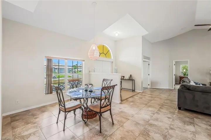 Vaulted ceilings in a dining area featuring large format tile flooring and a decorative arched window