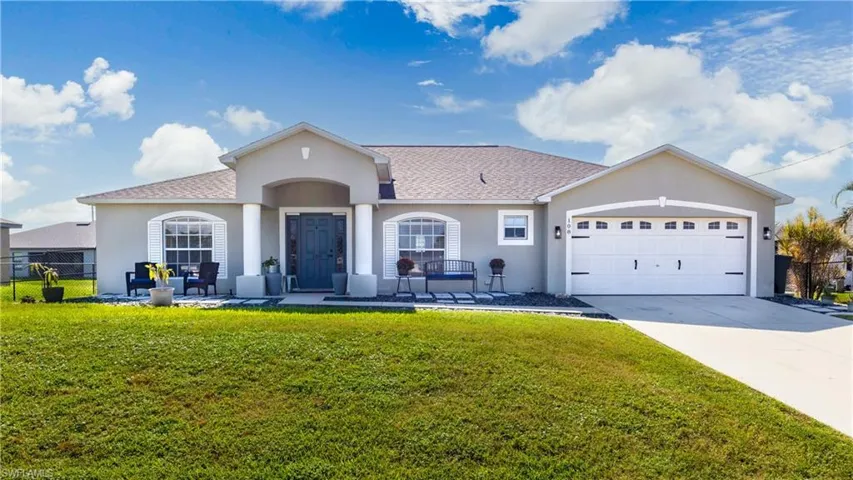 View of front facade with stucco siding, a front lawn, driveway, an attached garage, and roof with shingles
