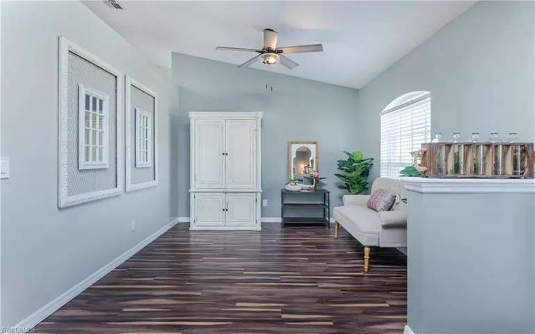 Sitting room with vaulted ceiling, dark wood-type flooring, and ceiling fan