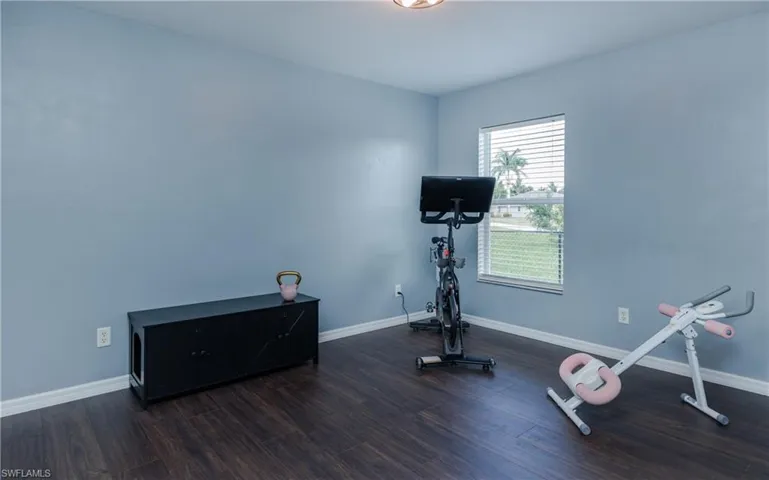 Bedroom styled as workout room with baseboards and dark wood-style floors