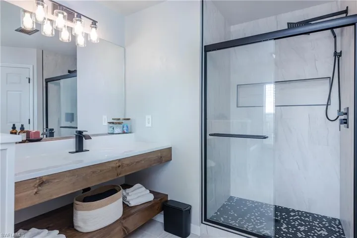 Bathroom with a marble finish shower, vanity, and tile patterned flooring