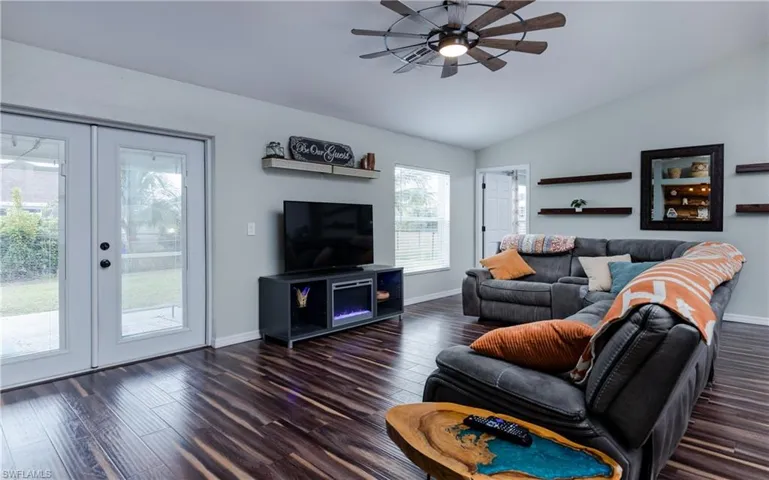 Living room with vaulted ceiling, dark wood-style flooring, ceiling fan, and french doors