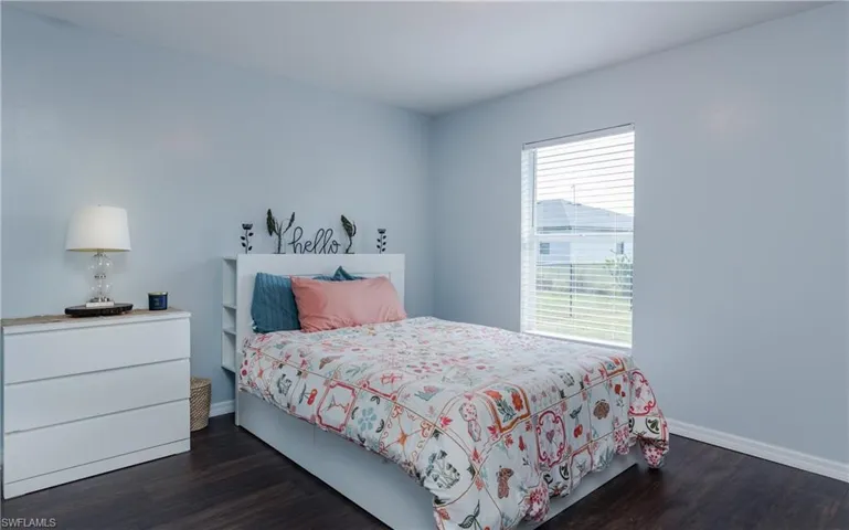 Bedroom featuring dark wood-style floors and baseboards