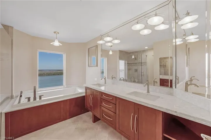 Bathroom with a stall shower, a bath, double vanity, and light tile patterned flooring