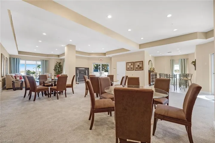 Community space featuring light carpet, plenty of natural light, a raised ceiling, and recessed lighting