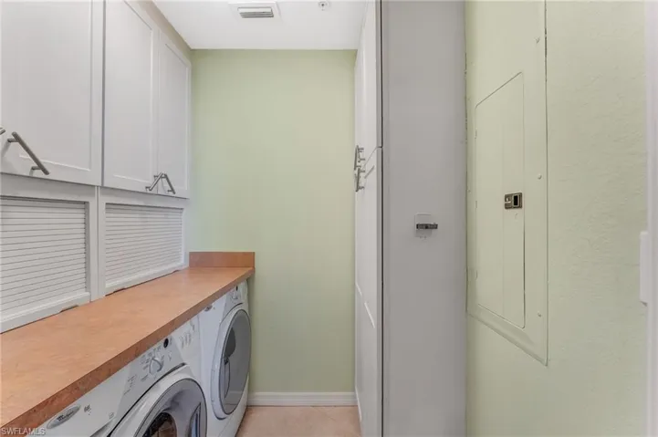 Laundry area with cabinet space, washing machine and dryer, and electric panel