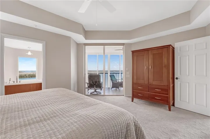 Carpeted primary bedroom featuring a ceiling fan and access to lanai
