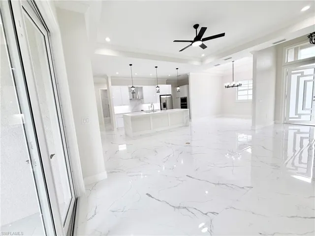 Unfurnished living room with a sink, light marble finish flooring, ornamental molding, recessed lighting, and ceiling fan