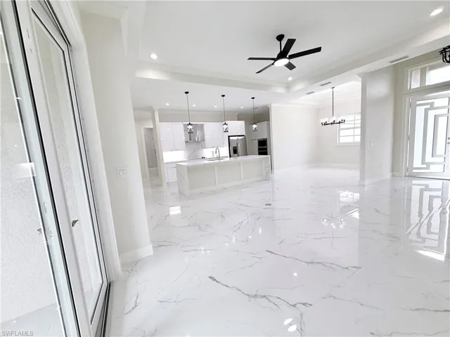 Unfurnished living room with a sink, crown molding, recessed lighting, ceiling fan, and light marble finish flooring