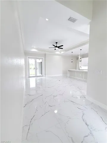Empty room featuring a raised ceiling, baseboards, ceiling fan, marble finish flooring, and recessed lighting