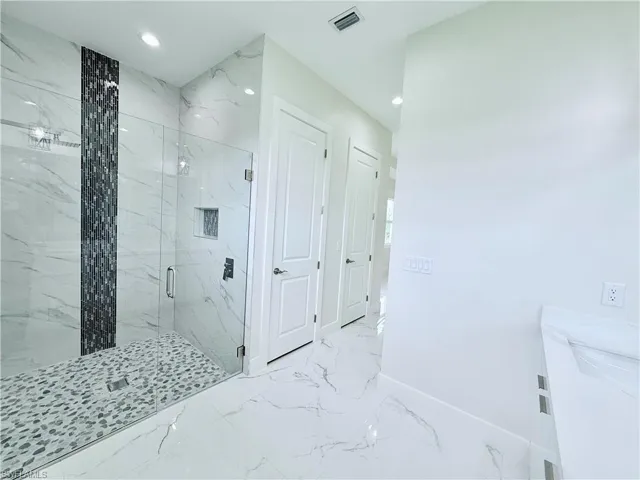 Bathroom featuring a marble finish shower, marble finish floors, baseboards, recessed lighting, and vanity