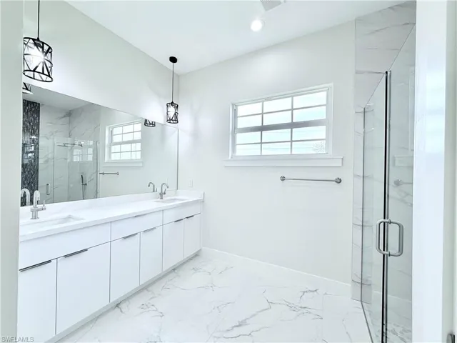 Full bathroom with marble finish floors, a marble finish shower, double vanity, baseboards, and recessed lighting