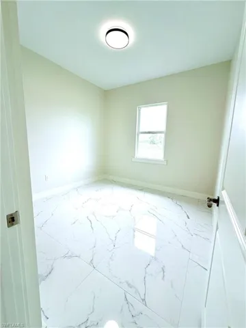 Empty room featuring marble finish flooring and baseboards