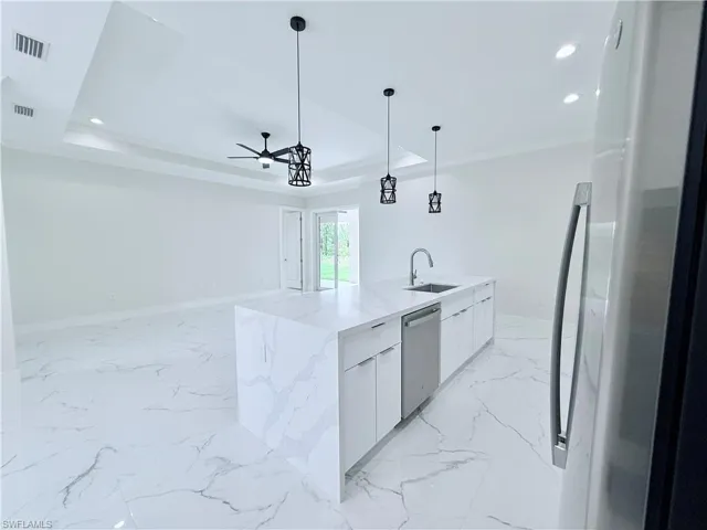 Kitchen with stainless steel dishwasher, freestanding refrigerator, modern cabinets, a sink, and a ceiling fan