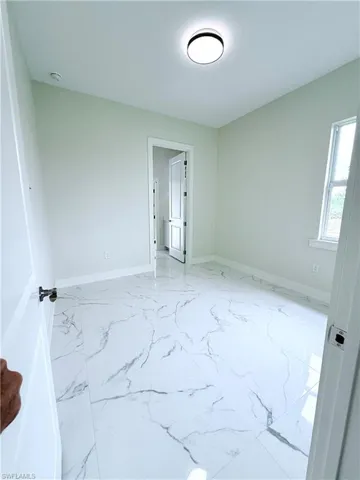 Spare room with marble look tiles and baseboards