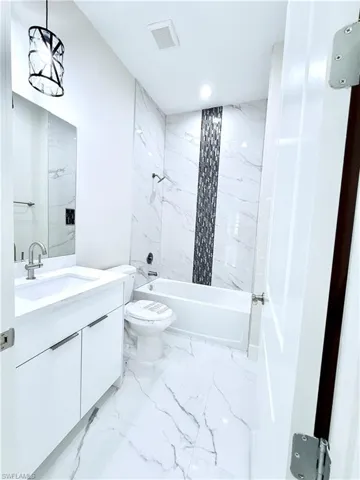 Full bathroom with marble finish flooring, vanity, toilet,  shower combination, and recessed lighting