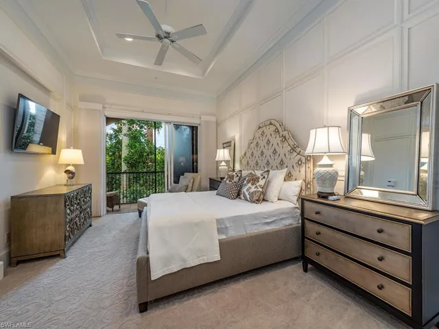 Carpeted bedroom featuring access to outside, ceiling fan, a decorative wall, a raised ceiling, and ornamental molding