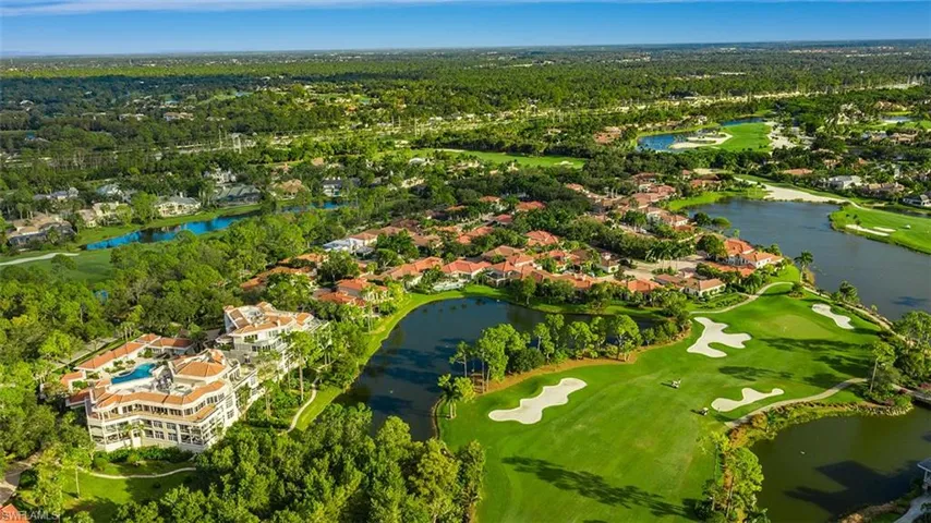 Aerial view of property's location featuring a golf course, a nearby body of water, and nearby suburban area