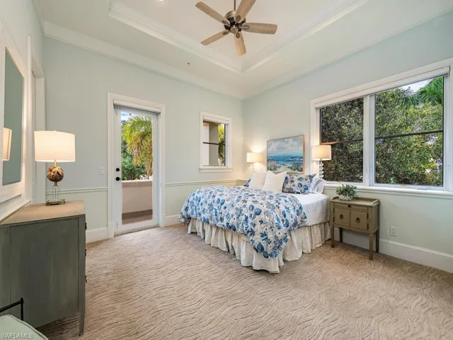 Bedroom with a raised ceiling, light carpet, multiple windows, and ornamental molding