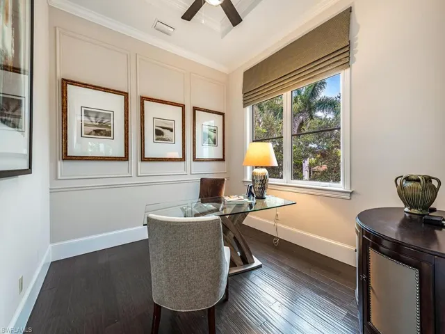 Office area featuring ornamental molding, dark wood-style flooring, a decorative wall, and a ceiling fan