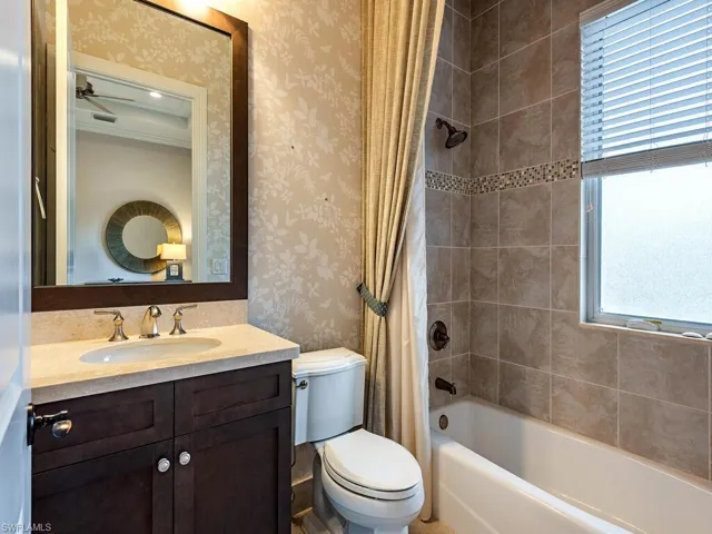 Full bath featuring shower / tub combo, vanity, wallpapered walls, and ceiling fan