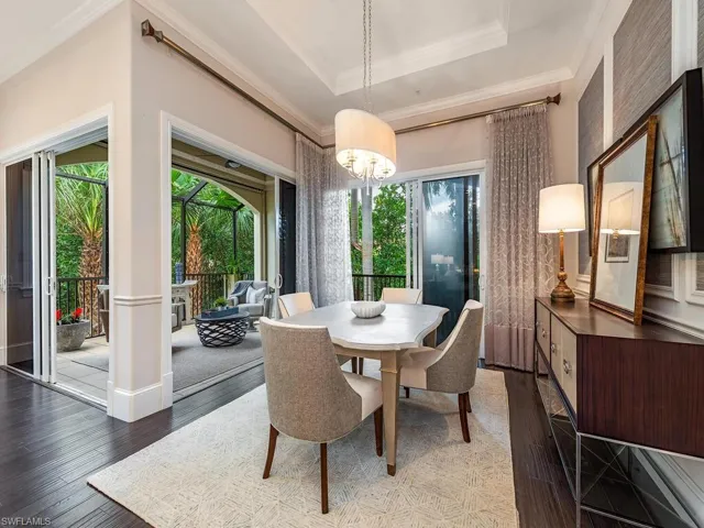 Dining area with ornamental molding, a raised ceiling, dark wood-style floors, and a chandelier