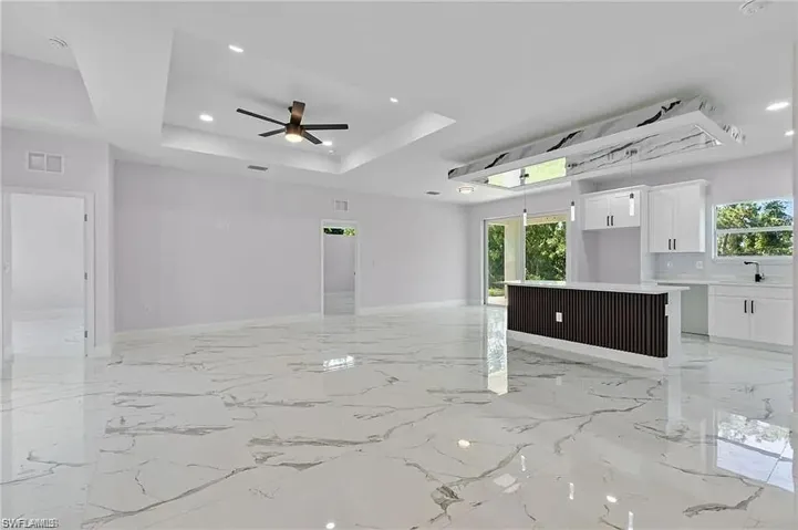 Unfurnished living room featuring visible vents, plenty of natural light, a tray ceiling, and a sink