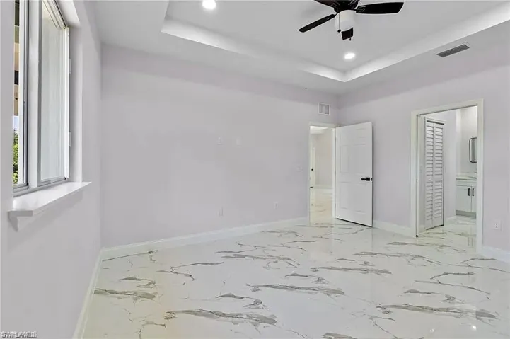 Unfurnished bedroom featuring baseboards, a tray ceiling, visible vents, and recessed lighting