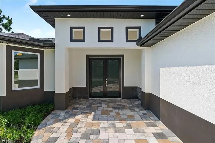 View of exterior entry featuring stucco siding, a patio, and french doors
