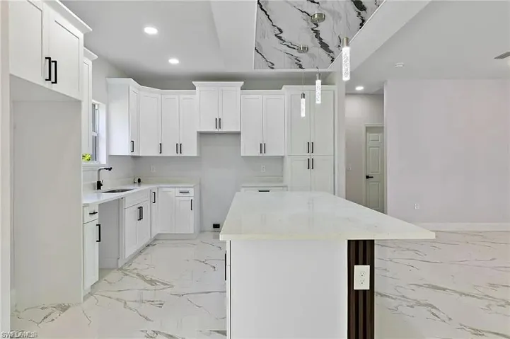 Kitchen with recessed lighting, marble finish floor, a sink, a kitchen island, and white cabinetry