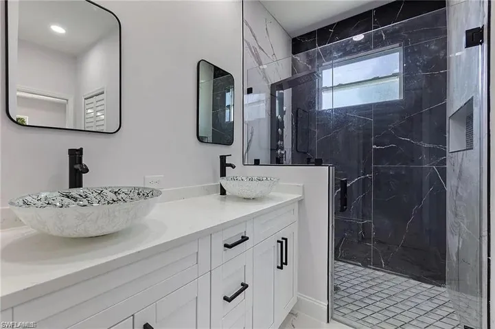 Full bath featuring double vanity, a marble finish shower, and a sink